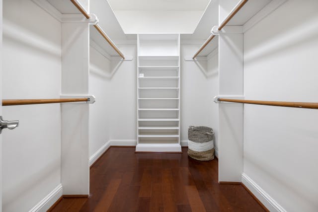 large-walk-in-closet-space-with-shite-walls-and-hardwood-floors